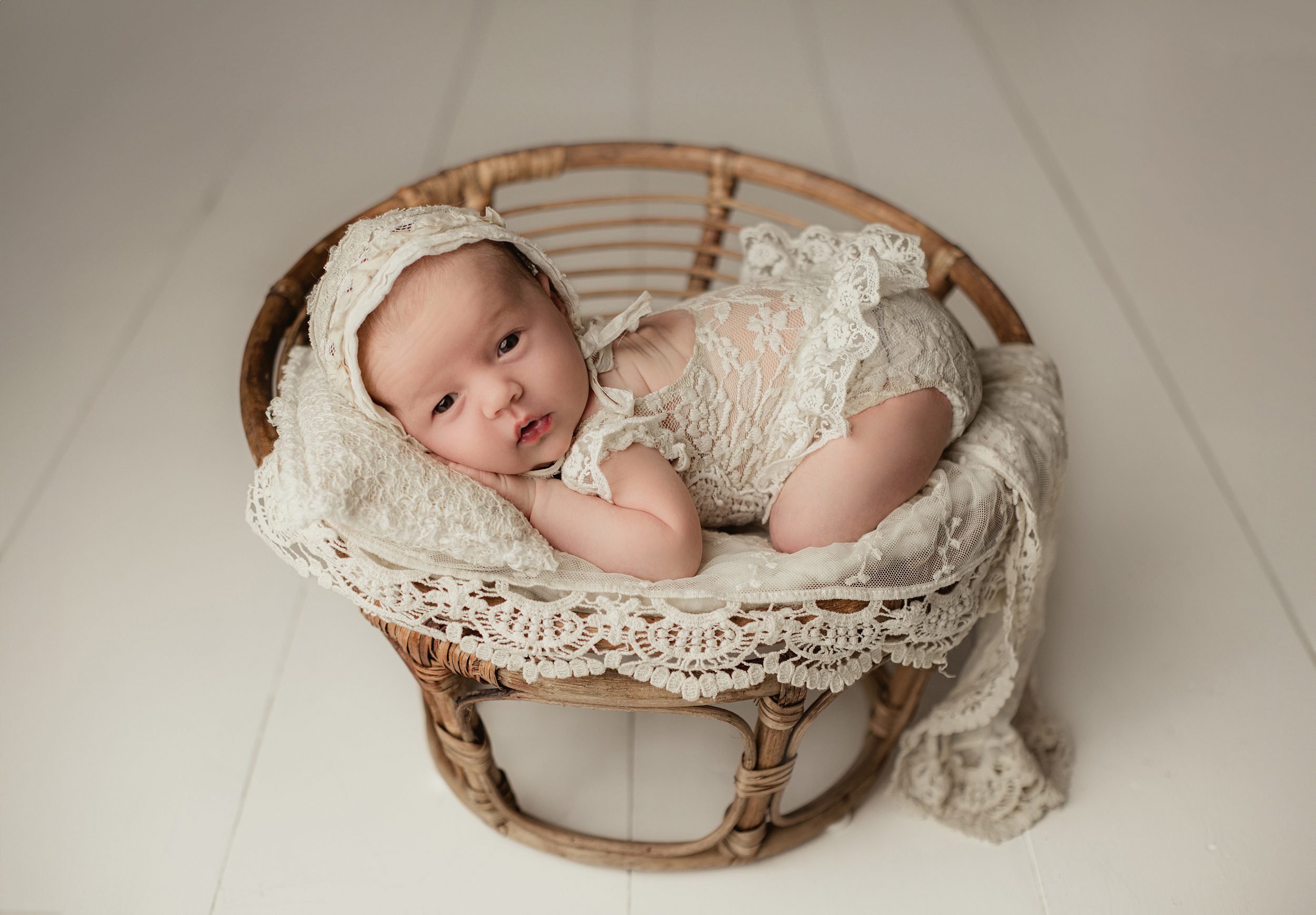 A newborn baby lays on a lace pillow and blanket in a wicker basket thanks to fertility centers of orange county