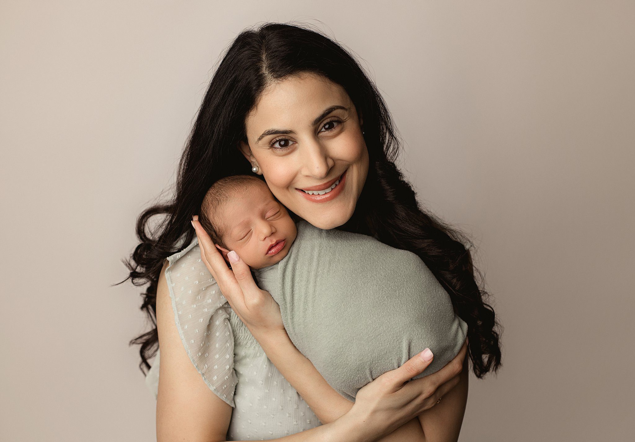 A mother cradles her sleeping newborn baby under her cheek while standing in a studio before some things to do in orange county with kids