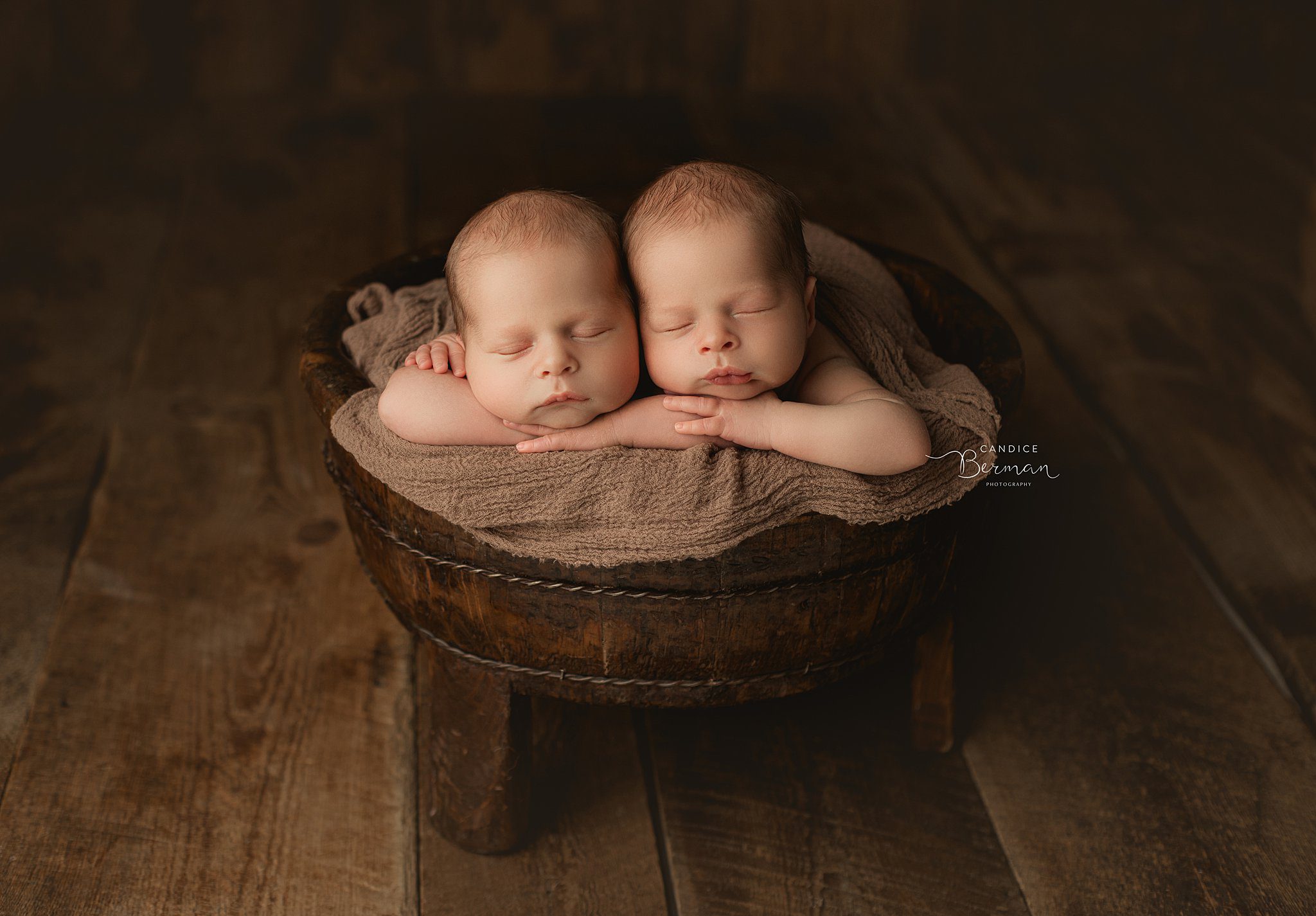 Newborn baby twins sleeps in a wooden bucket on a brown blanket in a studio before meeting orange county pediatricians