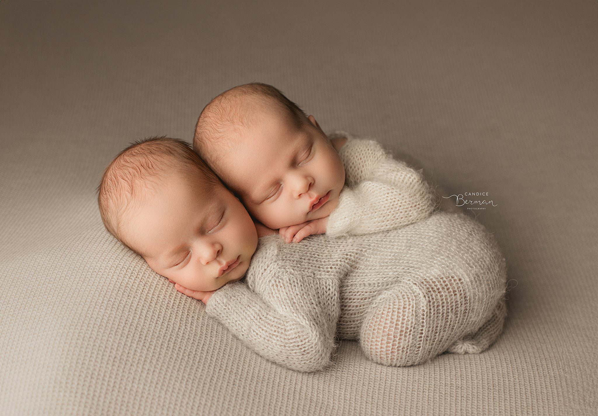 Sleeping newborn baby twins cuddle in knit onesies in a studio after meeting orange county pediatricians